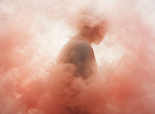 Una figura apenas visible entre niebla color salmón